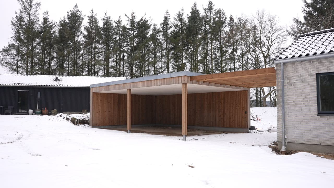 Ny carport ved træbeklædt hus, set skråt forfra